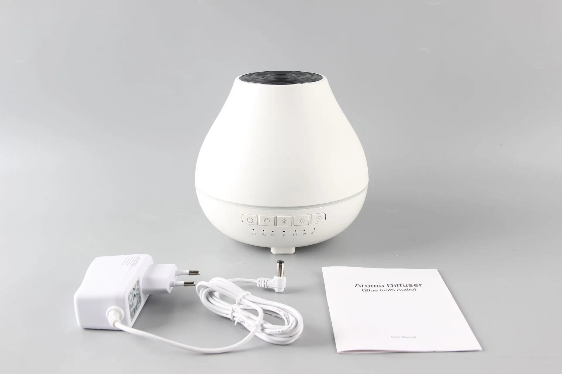 Round white Bluetooth humidifier and essential oil aroma diffuser with night light on a wooden surface.