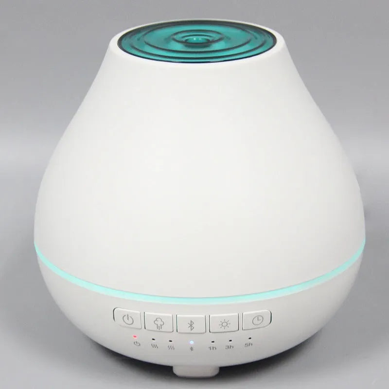 Round white Bluetooth humidifier and essential oil aroma diffuser with night light on a wooden surface.