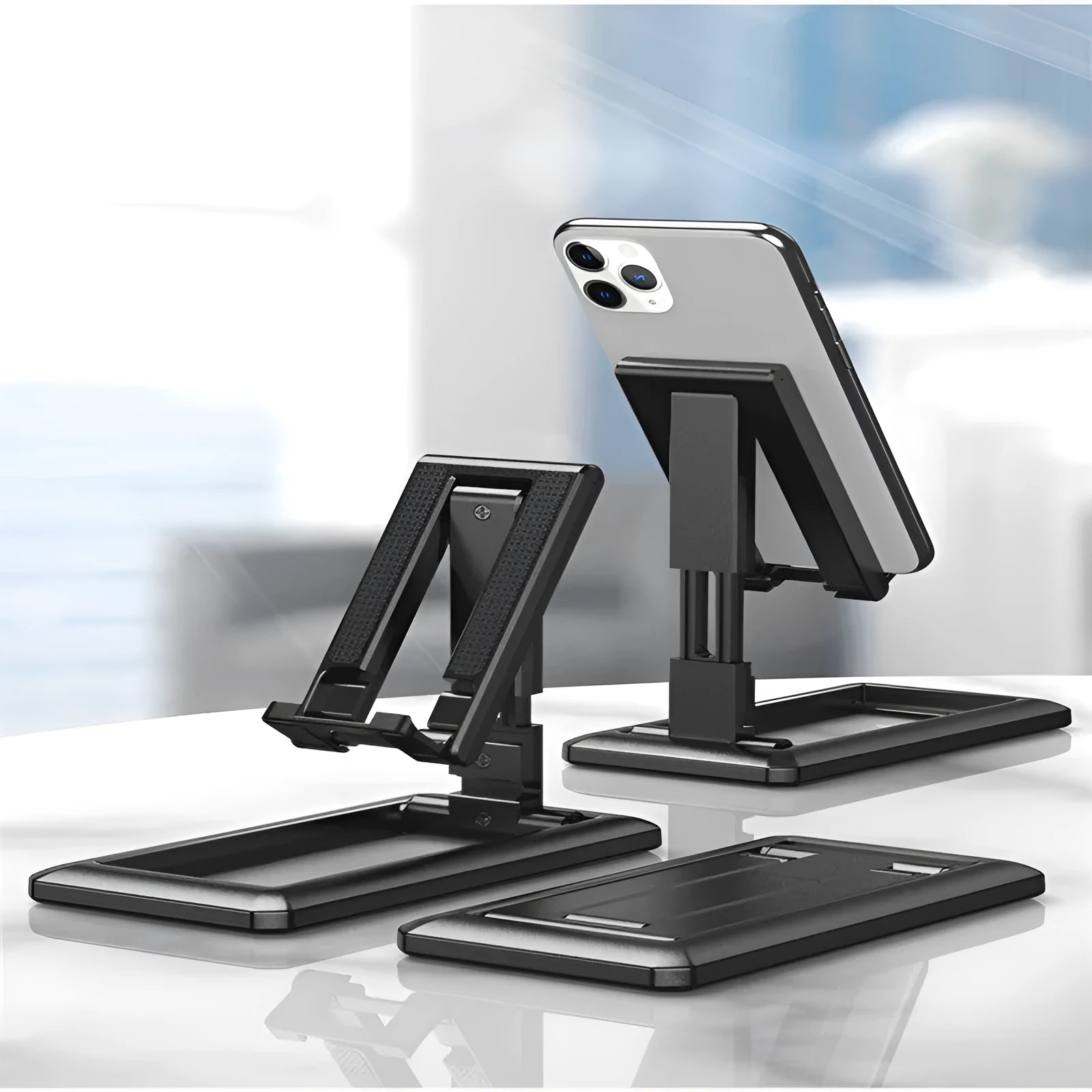 Retractable folding mobile phone desktop stand in black, shown extended in use and collapsed flat.