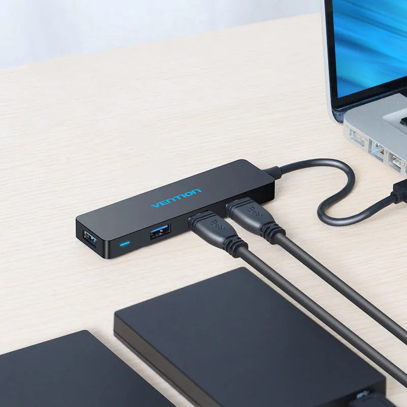 Black Wei Xun four-port USB 3.0 hub with short attached cable on a desk