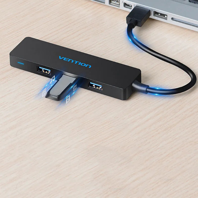 Black Wei Xun four-port USB 3.0 hub with short attached cable on a desk