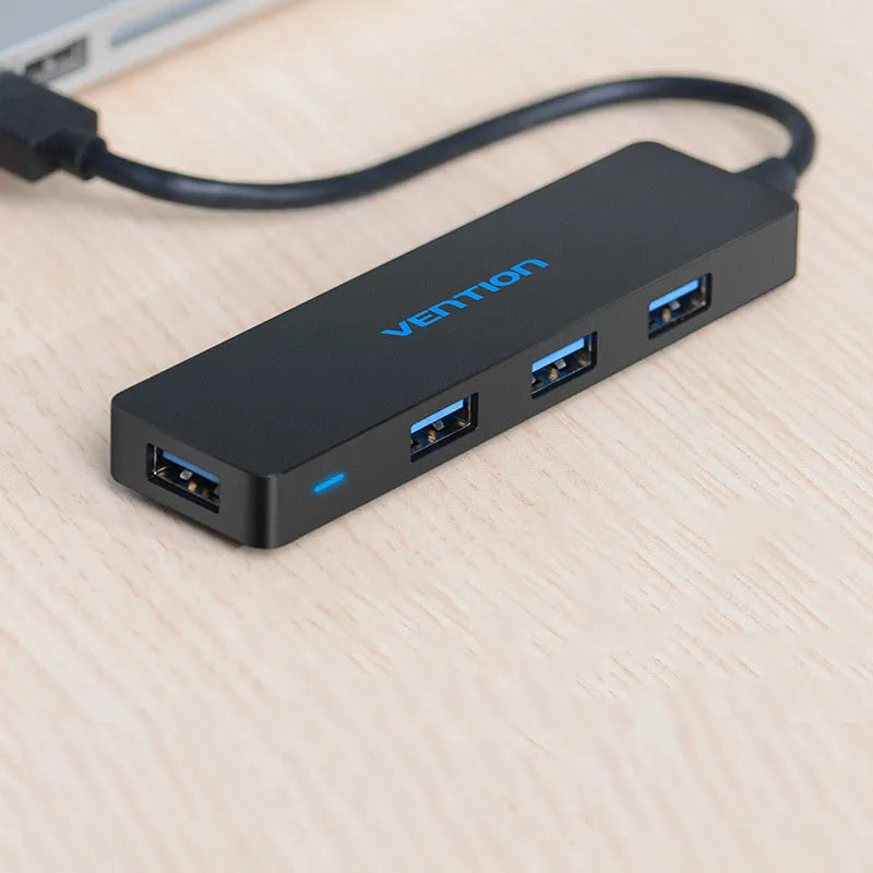 Black Wei Xun four-port USB 3.0 hub with short attached cable on a desk