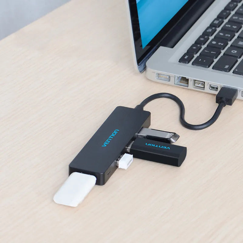 Black Wei Xun four-port USB 3.0 hub with short attached cable on a desk