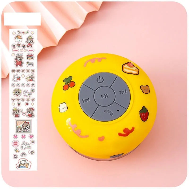 Small colourful waterproof Bluetooth mini speaker with a clear suction cup base mounted on a tile.