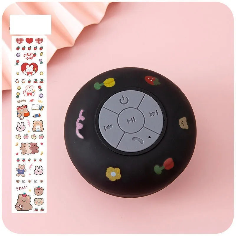 Small colourful waterproof Bluetooth mini speaker with a clear suction cup base mounted on a tile.