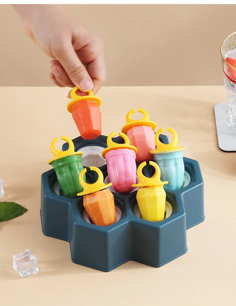 Soft plastic cartoon-style ice cube mould in brown and navy blue, showing honeycomb and rectangle shape options.