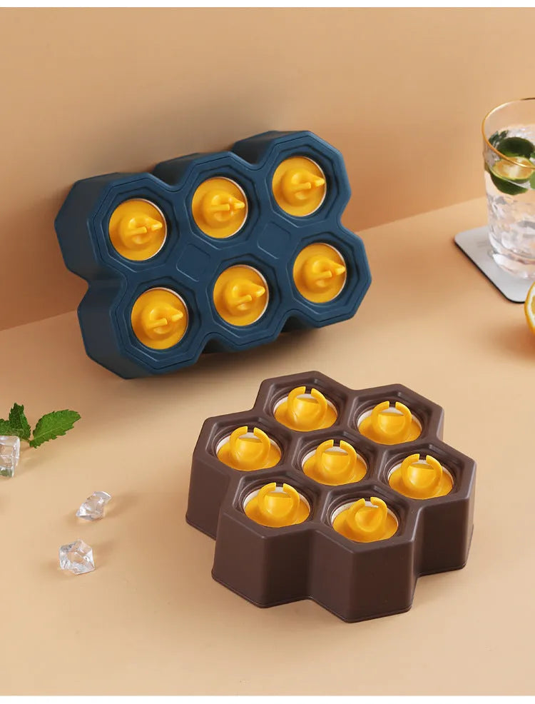 Soft plastic cartoon-style ice cube mould in brown and navy blue, showing honeycomb and rectangle shape options.