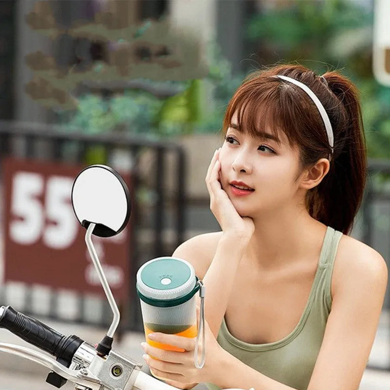Portable electric juicer cup in pink or green with USB charging cable and pulp residue box.