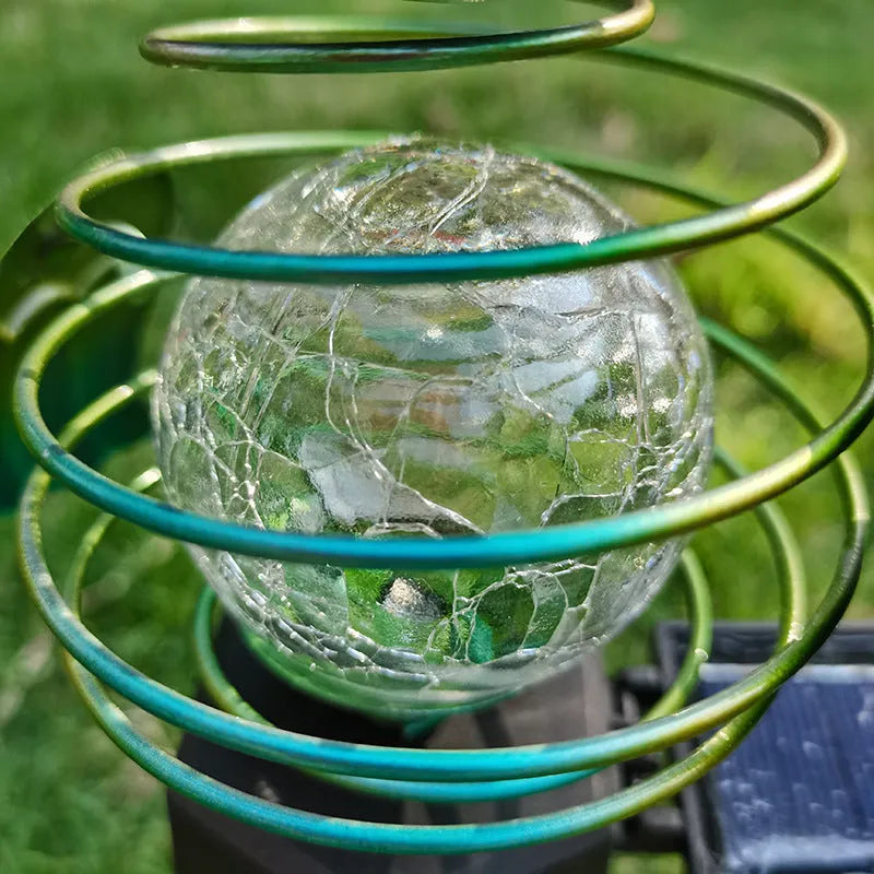 Solar-powered owl lawn lamp with iron sculpture and glass lampshade in a garden setting