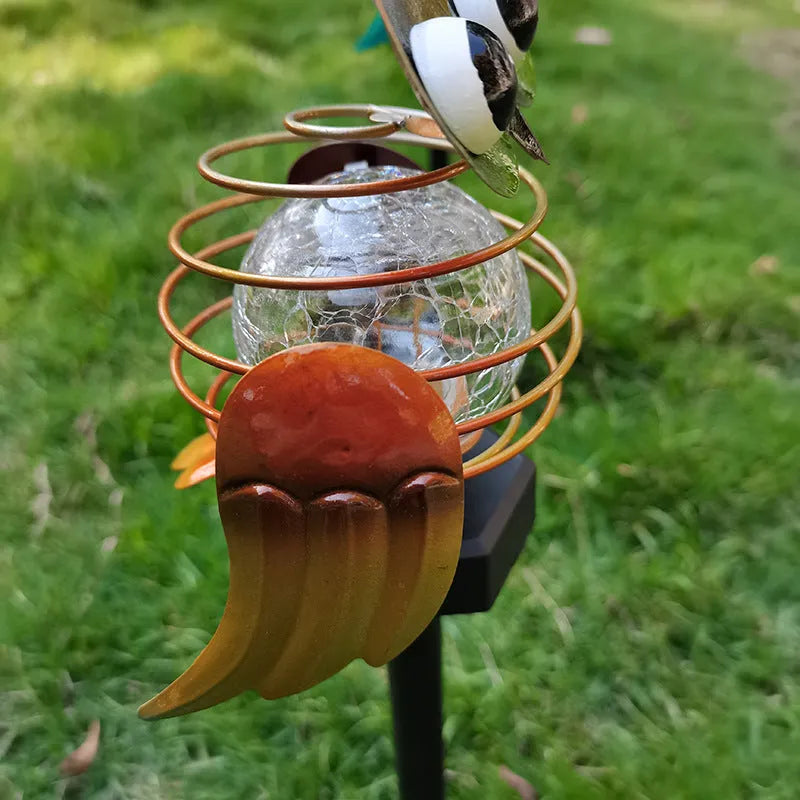Solar-powered owl lawn lamp with iron sculpture and glass lampshade in a garden setting