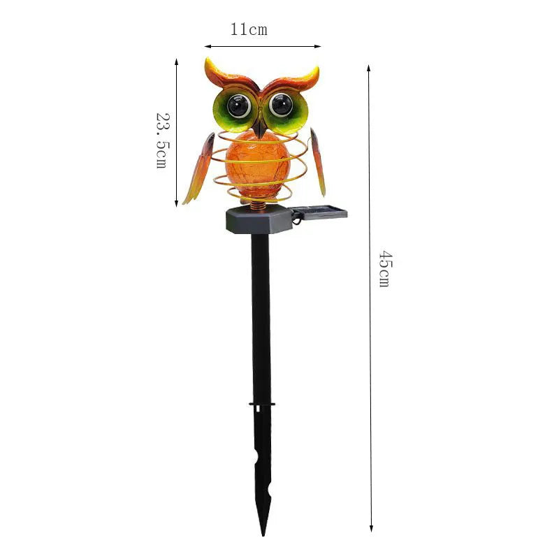 Solar-powered owl lawn lamp with iron sculpture and glass lampshade in a garden setting