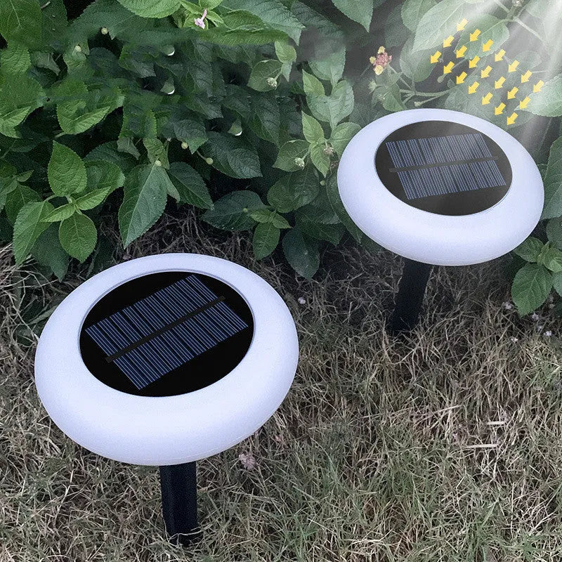 Round solar lawn light with colour gradient finish on garden soil near flowers