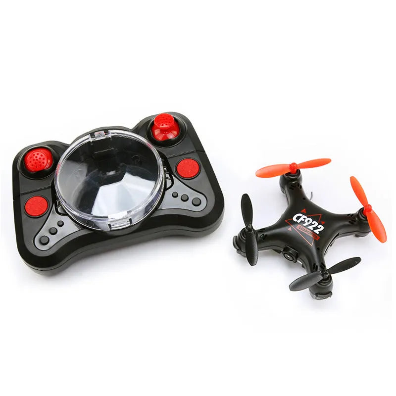 Compact black remote control aircraft with four rotors and a handheld remote control on a table.