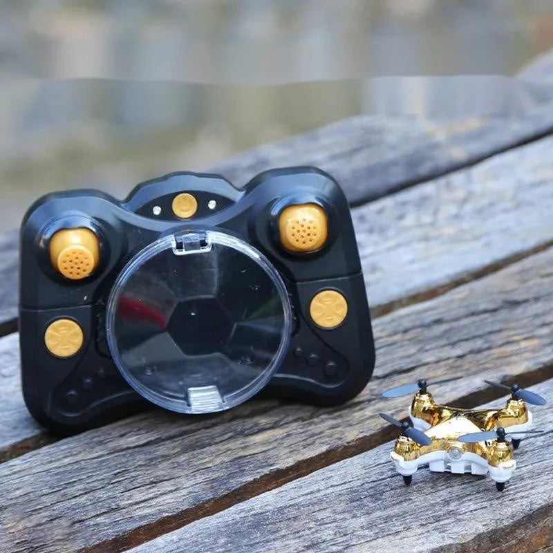 Compact black remote control aircraft with four rotors and a handheld remote control on a table.