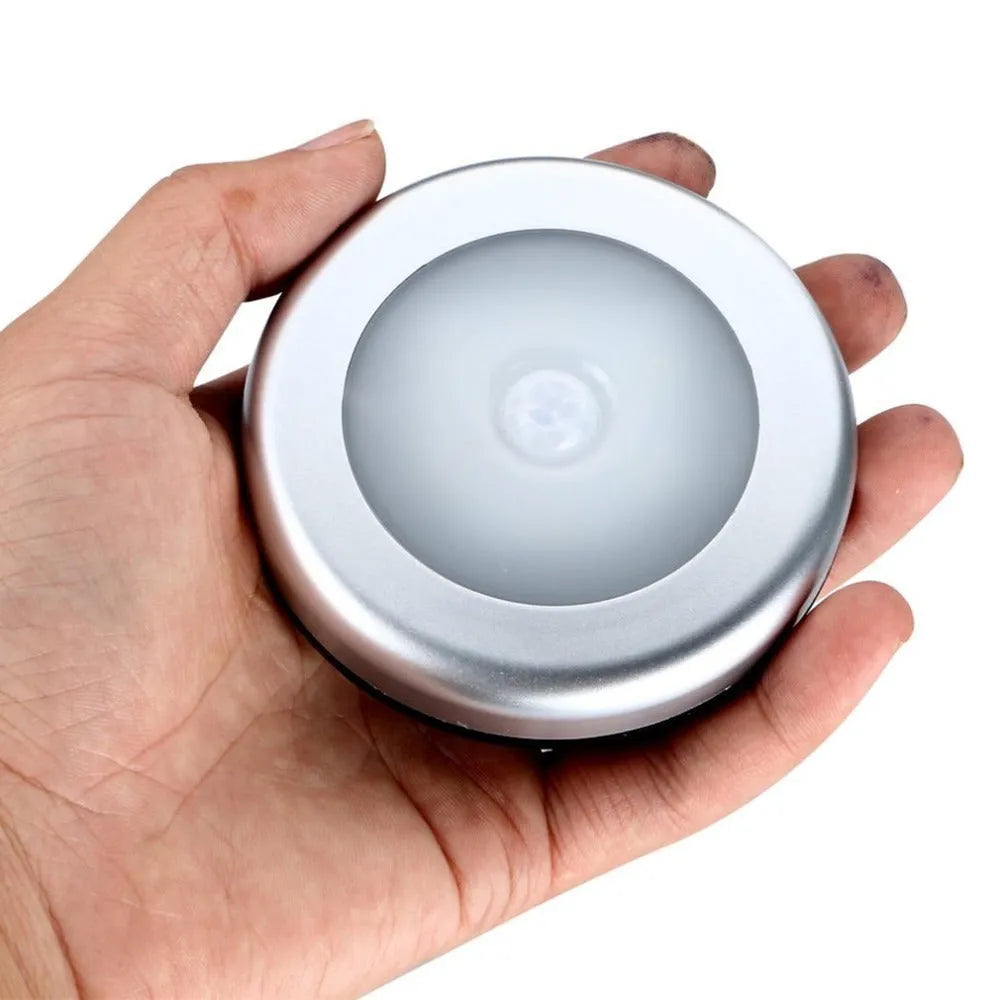Silver coloured circular wireless motion sensor night light on a wall.