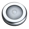Silver coloured circular wireless motion sensor night light on a wall.