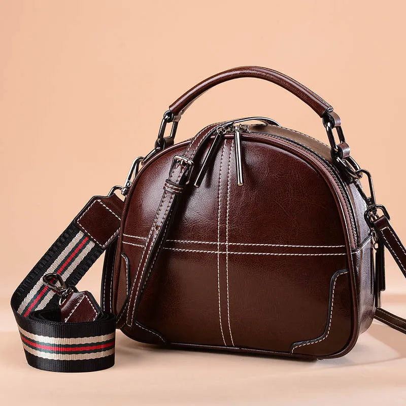 Round women's leather handbag in cowhide with soft double handles and zipper.