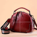 Simple round leather handbag with zipper and double soft handles in wine red colour