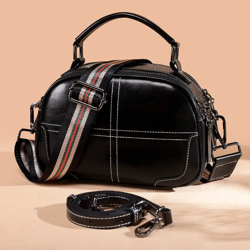 Round leather women's handbag with soft handle and zipper closure in wine red colour.