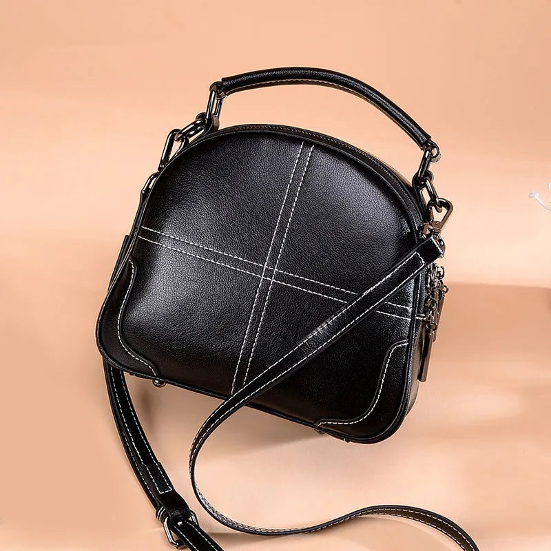 Round women's leather handbag in cowhide with soft double handles and zipper.