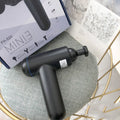 Black portable fascia gun massager with USB charging port and multiple massage heads.