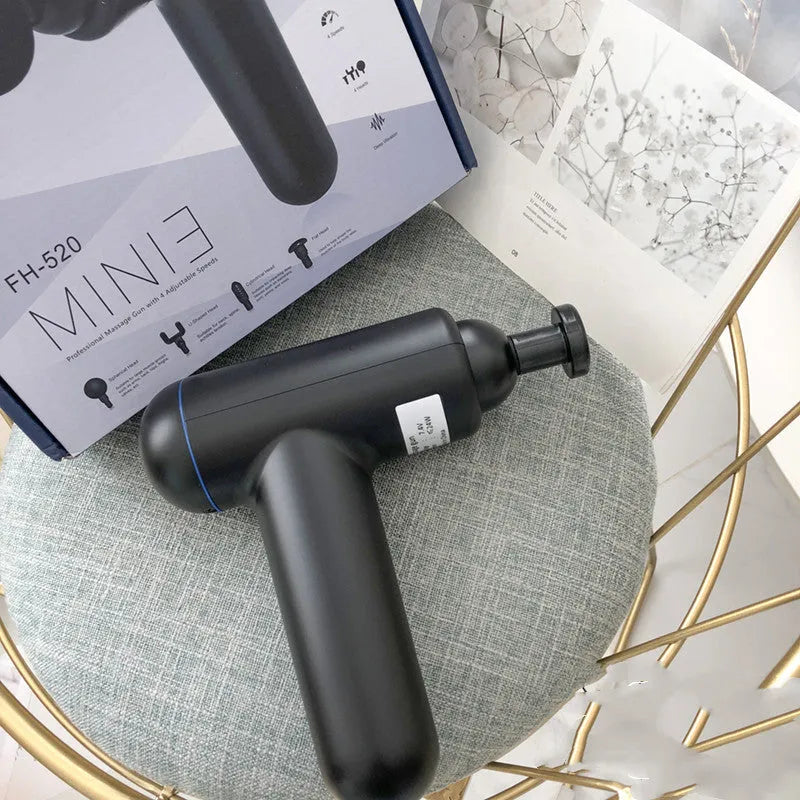 Black portable fascia gun massager with USB charging port and multiple massage heads.