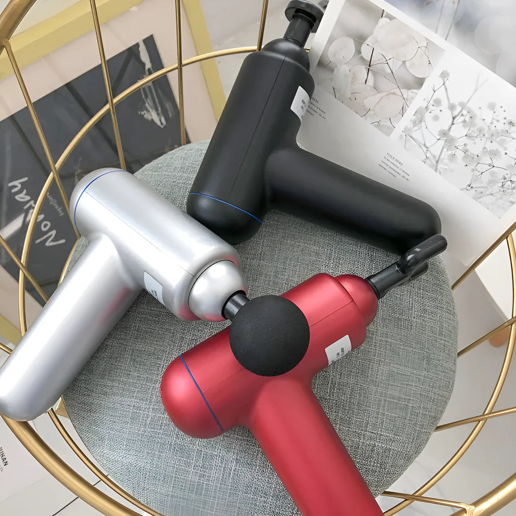 Black portable fascia gun massager with USB charging port and multiple massage heads.