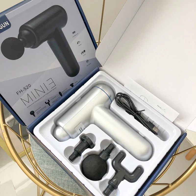 Black portable fascia gun massager with USB charging port and multiple massage heads.