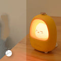 Portable cartoon-designed bedside night light with touch dimming control on a table.