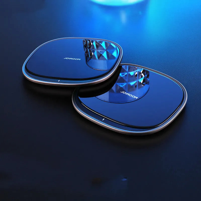 Black 15W wireless charging pad with zinc alloy rim and glass top on a wooden desk