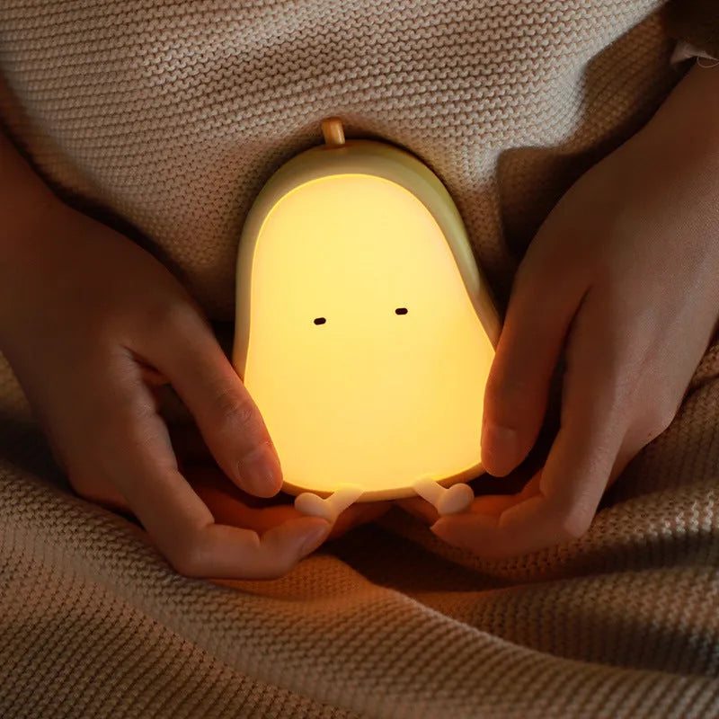 Yali warm yellow silicone pear night light on a wooden bedside table.