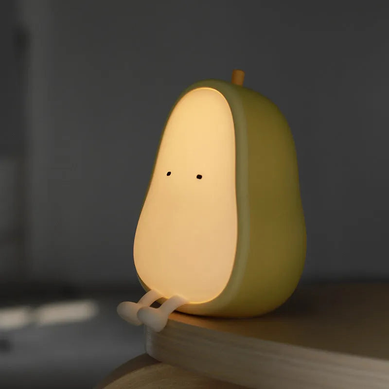 Yali warm yellow silicone pear night light on a wooden bedside table.