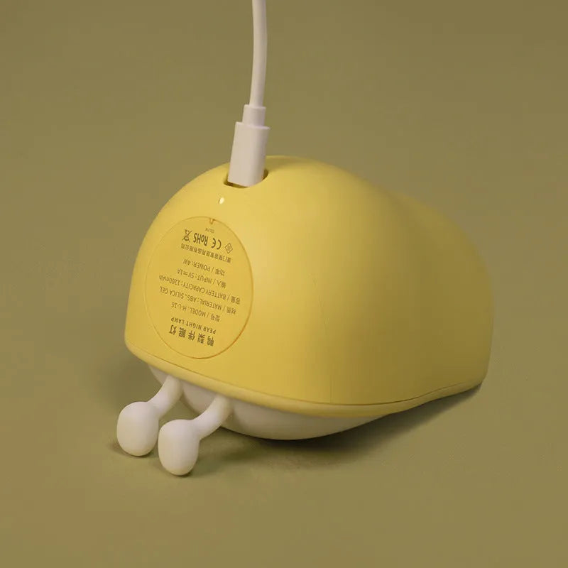 Yali warm yellow silicone pear night light on a wooden bedside table.