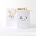 Small cardboard gift box with handbag and raffia in blue, pink, red, or white, showing bronzing detail.