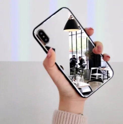 Black mirror phone case for Apple iPhone models X, 7 Plus, and 8 Plus on a table.