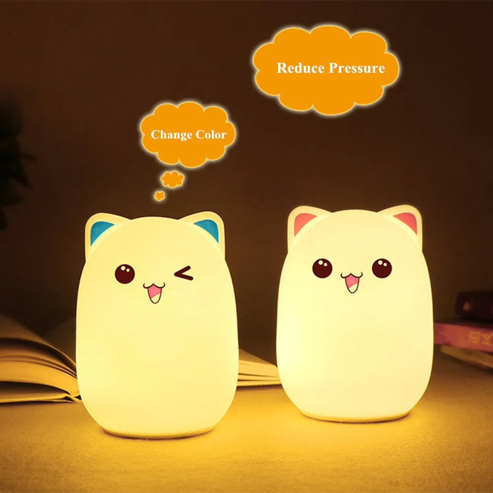 Cartoon silicone clapping night lamp in pink with USB charging cable on a bedside table