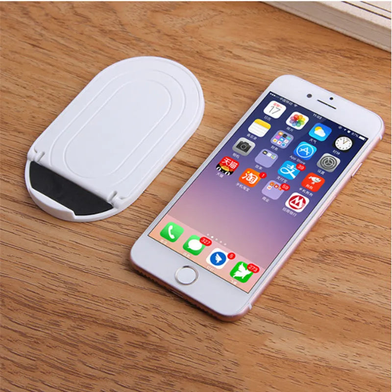 Plastic lazy bracket mobile phone stand in one of six colour options on a desk
