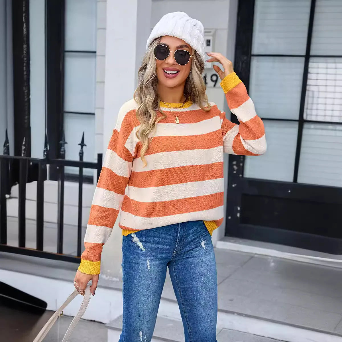 Women's loose blue acrylic sweater with stripes, round neck, and long sleeves on a hanger.