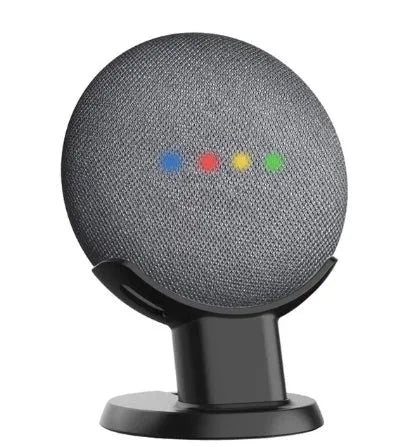 Black or white plastic stand holding a Google Home Mini voice assistant on a desk.