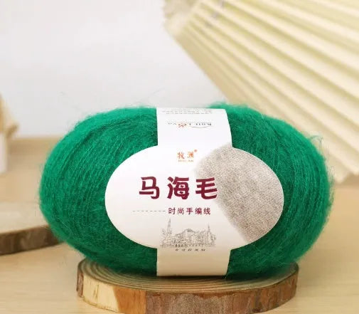 A ball of mohair yarn in a selected colour next to a hand-woven scarf example, showcasing the DIY kit.
