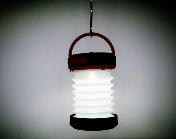 SolarBoom collapsible lantern in green with solar panel, collapsed for storage, on a wooden surface