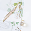Close-up of a metal bookmark with a real dried dandelion sealed inside, showing 12cm length.