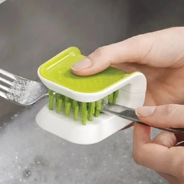 Blue U-shaped plastic brush for cleaning kitchen forks, knives and spoons on a countertop.