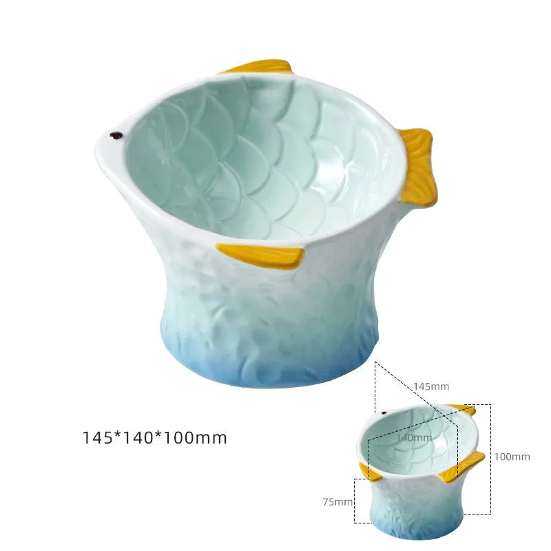 Set of blue fish-shaped ceramic cat bowls with a tilted angle on a wooden surface.