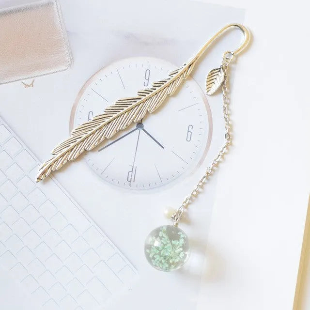 Flat metal bookmark with a dried flower inside, showing colour options like blue starry sky and dandelion.