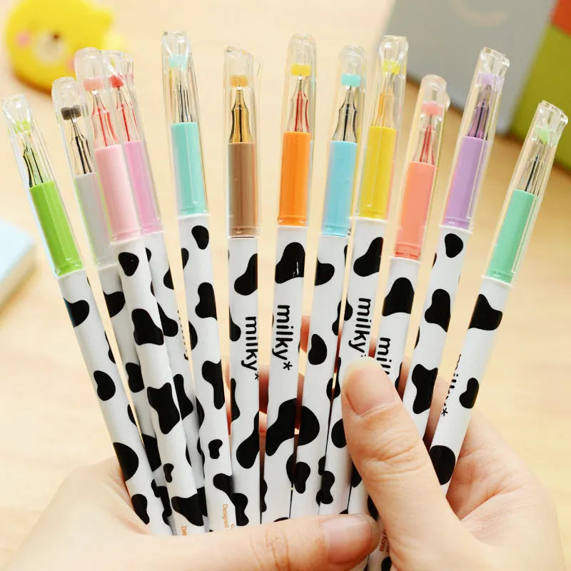 Set of 12 cow print design gel pens with 0.38mm tips in assorted colours laid out next to their box.