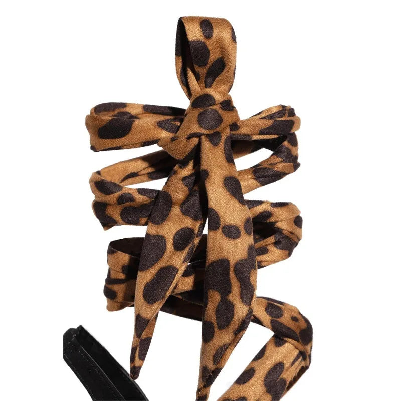 Light brown leopard print women's high heel sandals with cross straps and a thin stiletto heel on a white background.