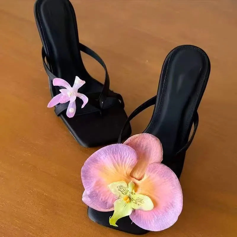 Handmade women's asymmetric flower sandals with high heel and square toe in black leather.