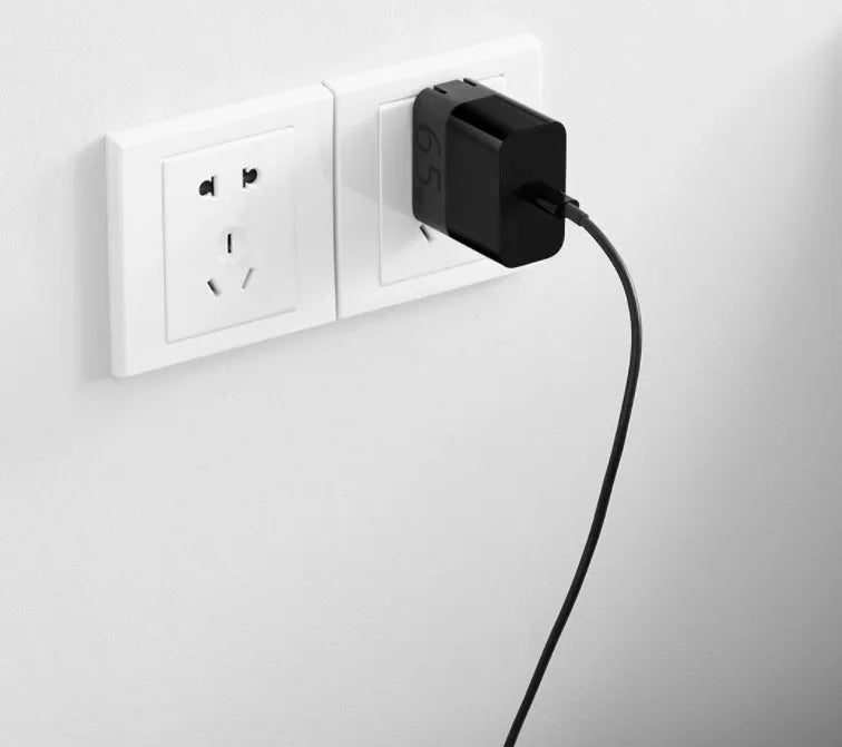 Black ZMI USB-C 65W notebook power adapter showing compact size next to a USB-C cable.