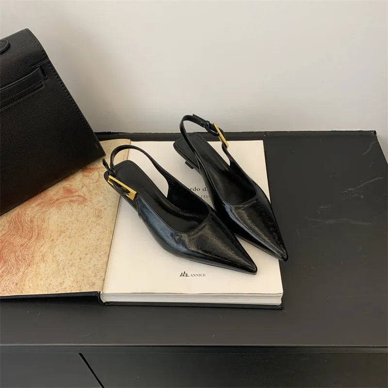 Women's black pointed toe leather strap shoes with a low rubber heel shown from the side.
